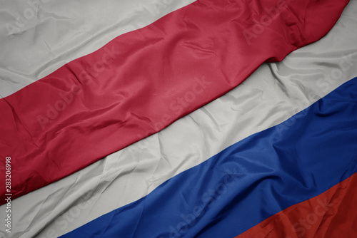 waving colorful flag of russia and national flag of poland.