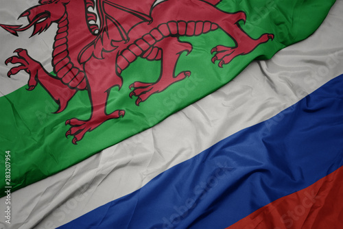 waving colorful flag of russia and national flag of wales.