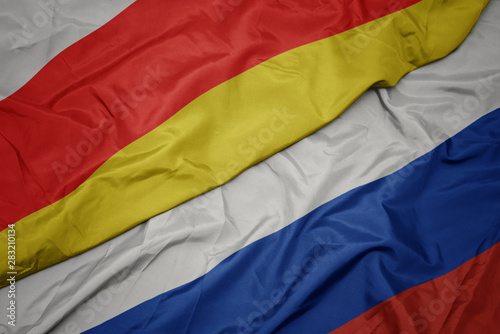 waving colorful flag of russia and national flag of south ossetia.