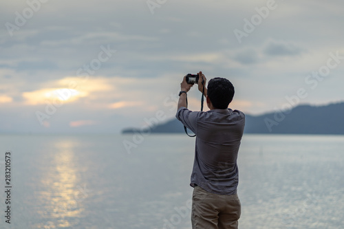 Young adult taking photo of amazing sunset light on the beach