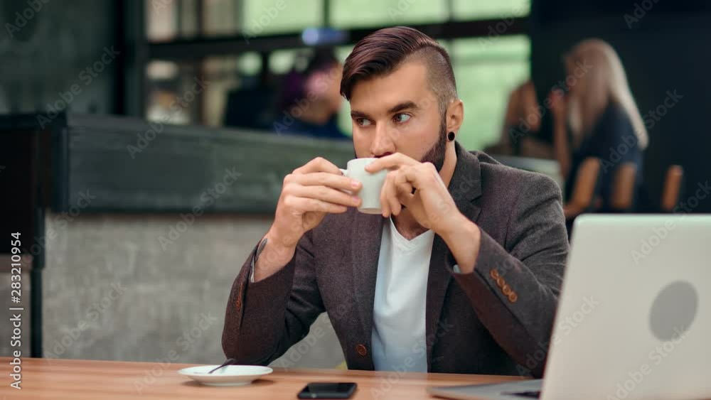 Focused handsome business male enjoying coffee break in cafe during working using laptop pc Focused handsome business male enjoying coffee break in cafe during working using laptop pc