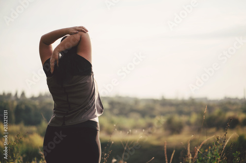 Overweight woman stretching hands relaxing while walking outdoors. Weight loss and active lifestyle concept