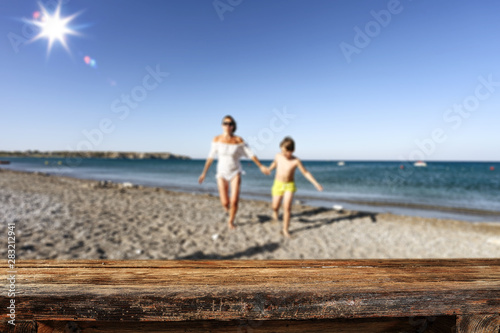 Table background with family having fun on the beach. Empty space for products and decoration.