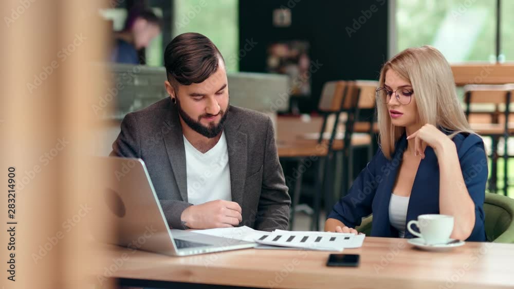 Businessman and businesswoman having informal business meeting at cafe discussing project Businessman and businesswoman having informal business meeting at cafe discussing project