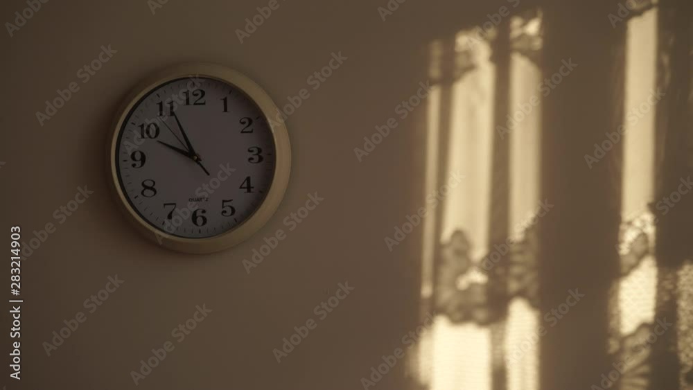 Clock ticking showing ten hours in morning, sunlight from window and shadows on wall. Time deadline concept. Time lapse