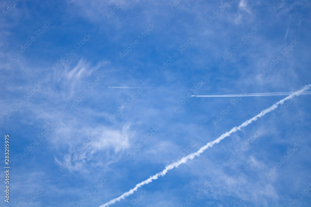Airplane flying in the blue sky among clouds and sunlight Airplane flying in the blue sky among clouds and sunlight