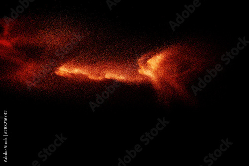 Abstract explosion of orange dust on black background. Freeze motion of orange powder splashing.