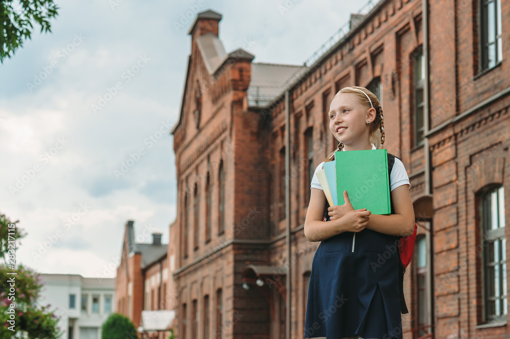 Portrait of schoolgirls with books in their hands. Against the background of an old building. Back to school concept.