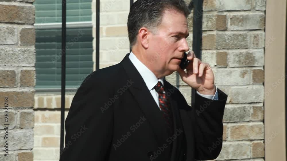 A businessman outside using wireless technology to converse with someone. A businessman outside using wireless technology to converse with someone.