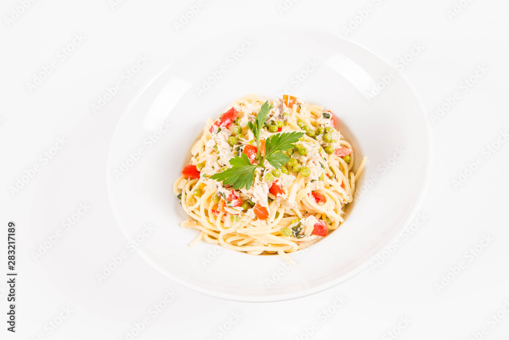 Spaghetti with cream sauce with smoked mackerel, peas ,bell pepper and some parsley on a white plate on a white background Spaghetti with cream sauce with smoked mackerel, peas ,bell pepper and some parsley on a white plate on a white background