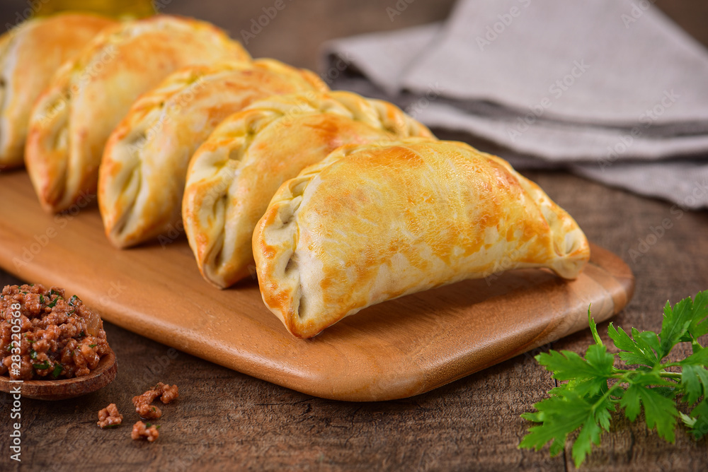 Meat roasted empanas on wooden background