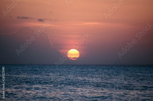 Fototapeta Naklejka Na Ścianę i Meble -  Закатное солнце над спокойной морской водой в розовых вечерних облаках