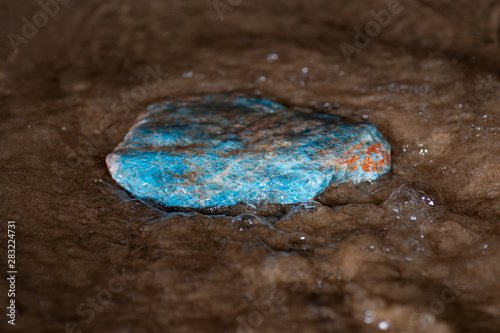Fotografía High grade rough natural Blue Apatite Specimen from Madagascar on wet sand  in front of the lake at sunrise