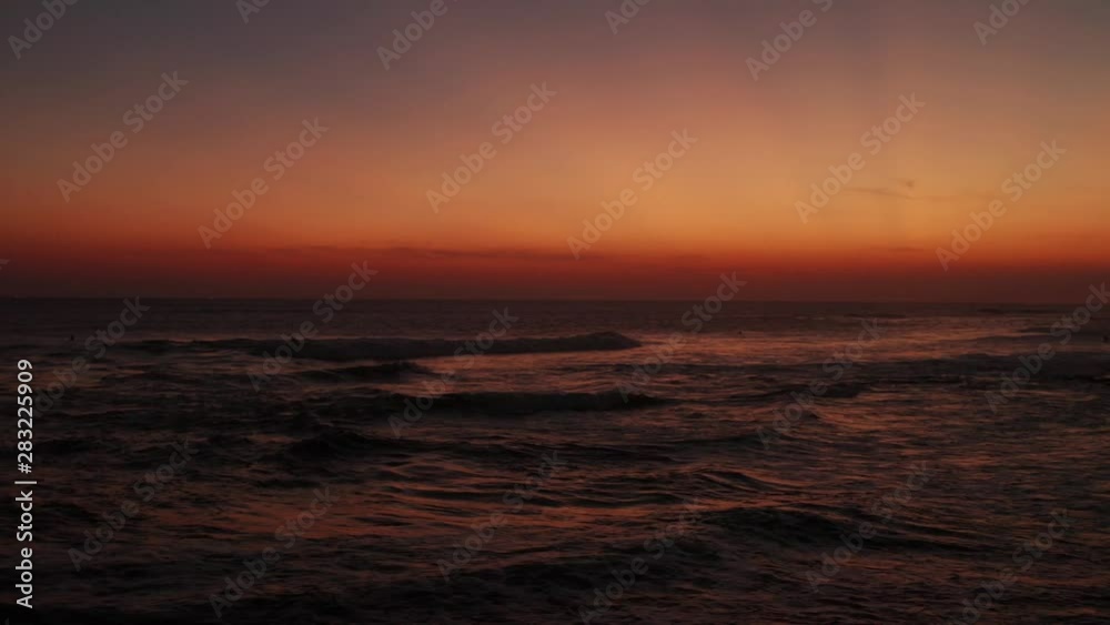 Aerial drone view silhouettes of surfing people over beautiful golden sunset sky background Aerial drone view silhouettes of surfing people over beautiful golden sunset sky background
