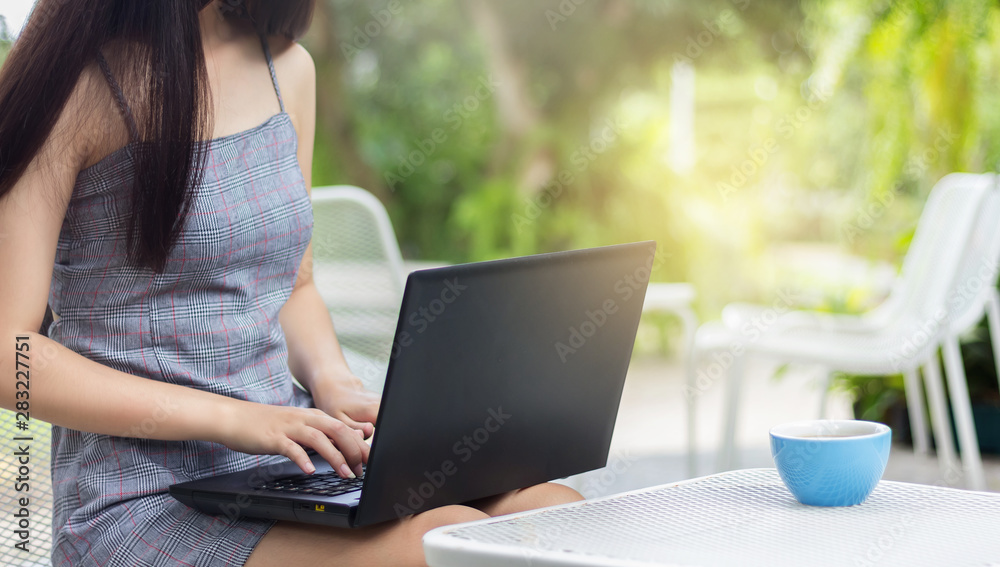 Young asian woman placed the laptop on the lap and working in outdoor garden Young asian woman placed the laptop on the lap and working in outdoor garden