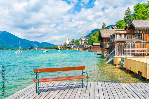 A bench on wooden deck by Lake St. Wolfgang in the Salzkammergut resort region with a view of St. Wolfgang market town, Austria