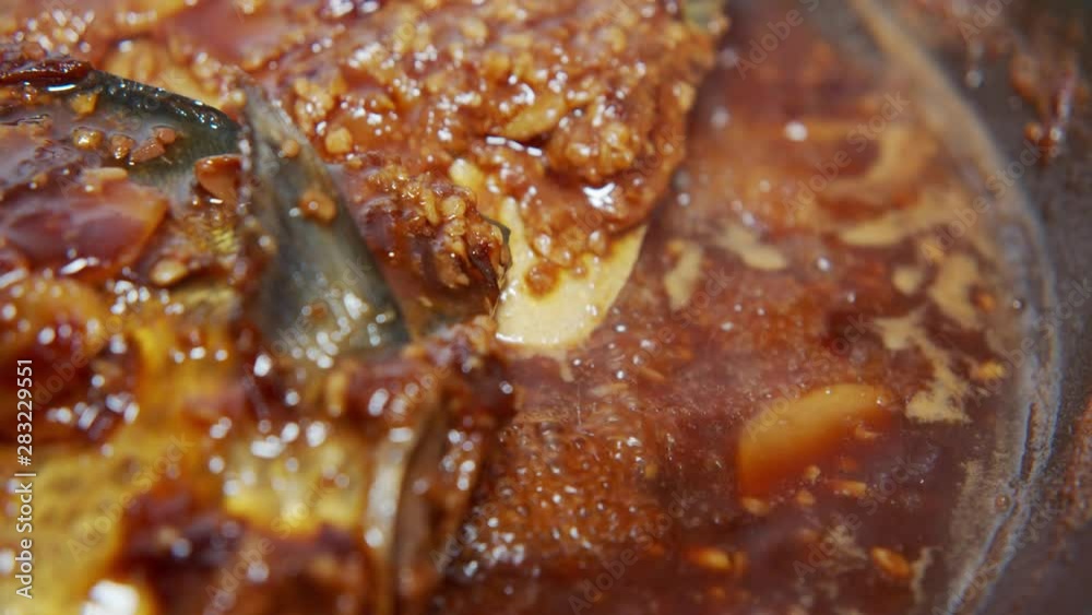 A Japanese female chef pouring miso over mackerel in the pan at home kitchen, Tokyo, Japan. May 2019. Camera fixed, Extreme close-up, high angle A Japanese female chef pouring miso over mackerel in the pan at home kitchen, Tokyo, Japan. May 2019. Camera fixed, Extreme close-up, high angle