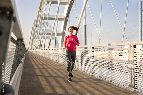 Beautiful young woman running on a bridge © Marko