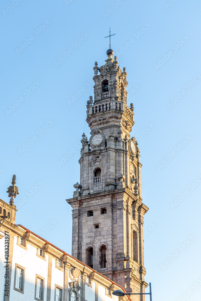 View of the beautiful baroque Church of Clerigos (Igreja dos Clerigos, in Portuguese) and iconic Clerigos Tower, one of the landmarks and symbols of Oporto city in Portugal. Sunset color in blue sky.