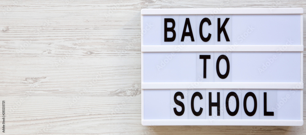 Education concept. 'Back to school' words on a lightbox over a white wooden background, top view. From above, overhead. Copy space. Education concept. 'Back to school' words on a lightbox over a white wooden background, top view. From above, overhead. Copy space.