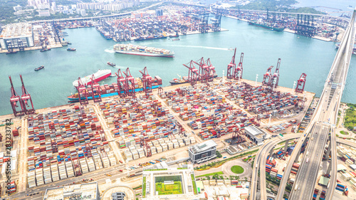 Hong Kong port industrial district with cargo container ship, cranes, car traffic on road and Stonecutters bridge. Logistic industry or freight transportation business concept