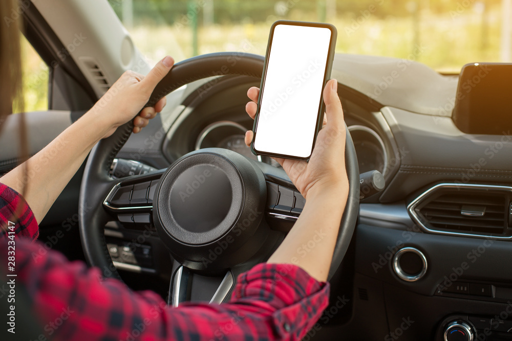 Beautiful woman sitting on the front driver seats in the car. Girl is using a smartphone. Hand closeup