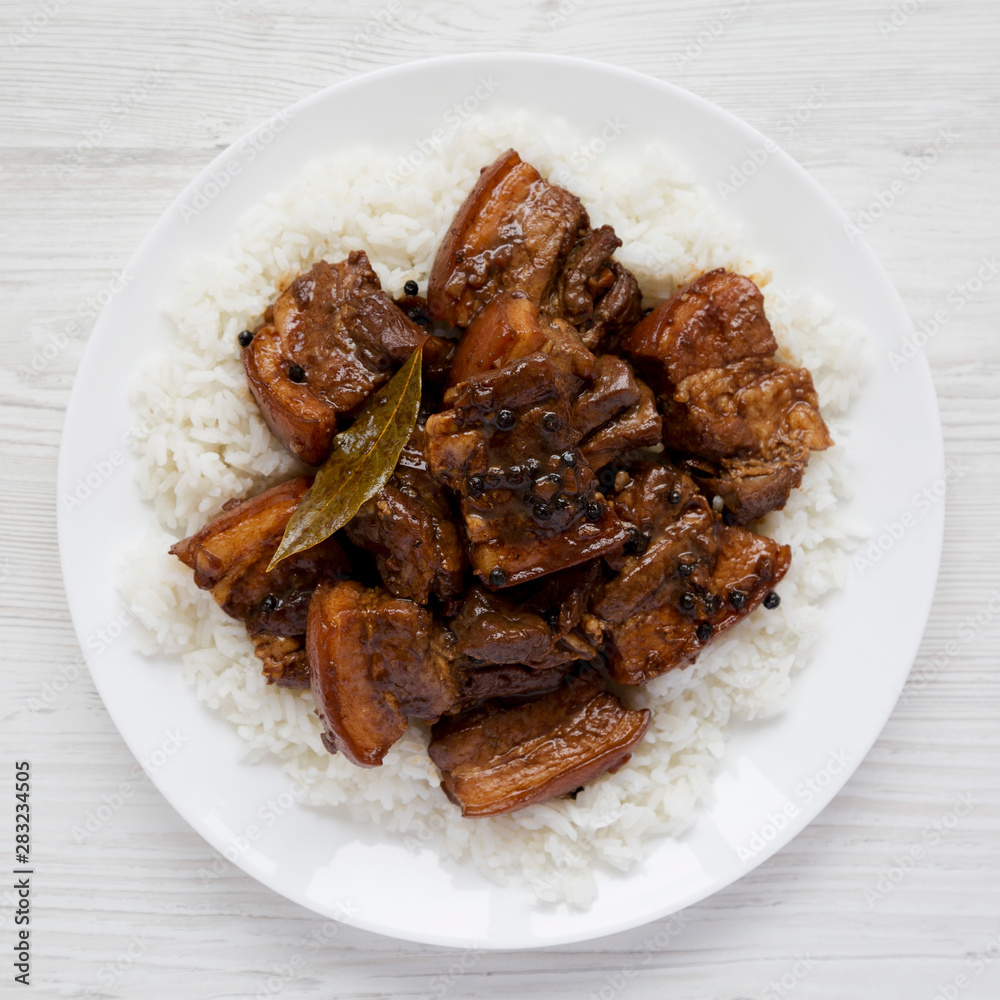 Homemade Filipino Adobo Pork with rice on a white plate over white wooden background, top view. Flat lay, overhead, from above. Close-up. Homemade Filipino Adobo Pork with rice on a white plate over white wooden background, top view. Flat lay, overhead, from above. Close-up.