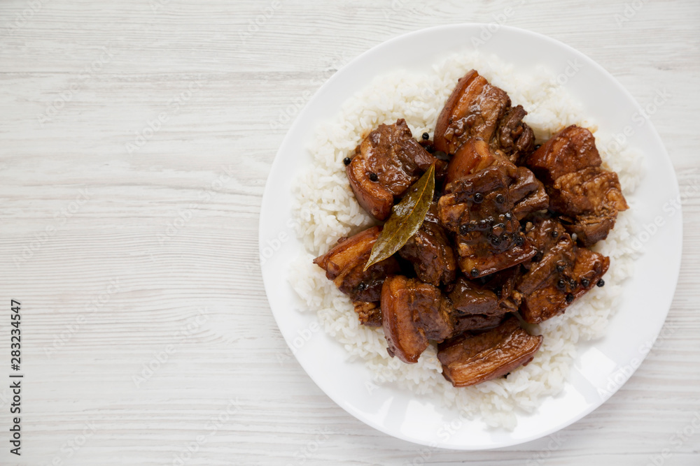 Homemade Filipino Adobo Pork with rice on a white plate over white wooden background, top view. Flat lay, overhead, from above. Copy space. Homemade Filipino Adobo Pork with rice on a white plate over white wooden background, top view. Flat lay, overhead, from above. Copy space.