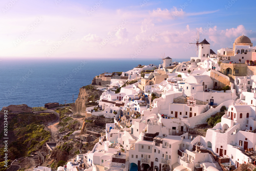 Santorini, Greece, April 2019. White traditional Greek houses on a hillside on the island of Santorini. Tourists are waiting for sunset. Sunset in the city of Oia, Santorini.
