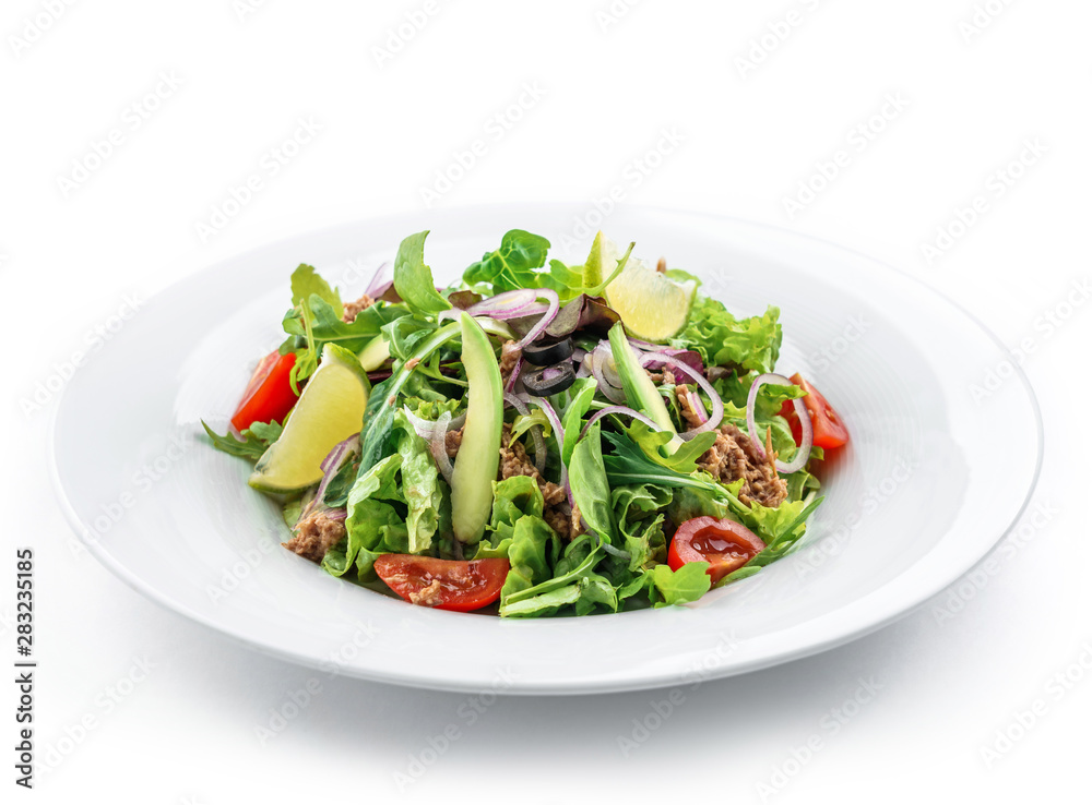 Green salad with arugula, lettuce, tomatoes, avocado, lime, tuna and olives in plate on isolated white background. Healthy food, clean eating, dieting