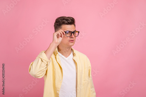 Portrait of young laughing  man and in glasses over pink background. Young handsome man with great smile wearing fashion eyeglasses against  background