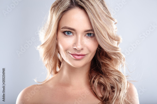 Fotografie Blonde young woman with healthy curly hair and natural make up