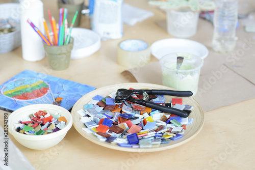 Process of making a mosaic picture from ceramic tile. The man organizes with a tweezers a puzzle of ceramic elements to build a picture.