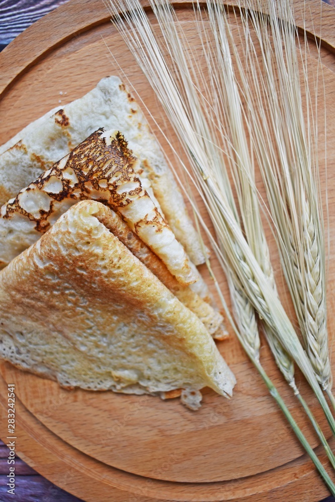 Delicious pancakes and wheat ears on a wooden background. Delicious pancakes and wheat ears on a wooden background.