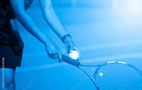 A tennis player prepares to serve a tennis ball during a match. Blue filter © Augustas Cetkauskas