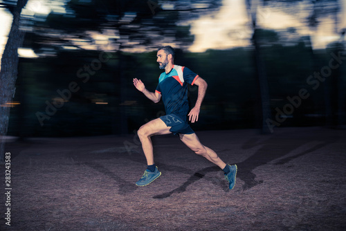 Middle aged caucasian man trail runner training fast speed in the forest © ROM