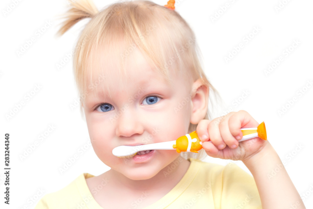 Little beautiful girl with blue eyes and pigtails brushes her teeth on a white background, close-up, isolate Little beautiful girl with blue eyes and pigtails brushes her teeth on a white background, close-up, isolate