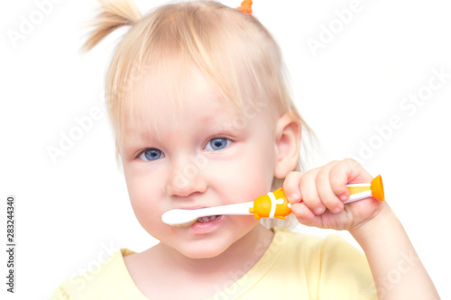 Little beautiful girl with blue eyes and pigtails brushes her teeth on a white background, close-up, isolate