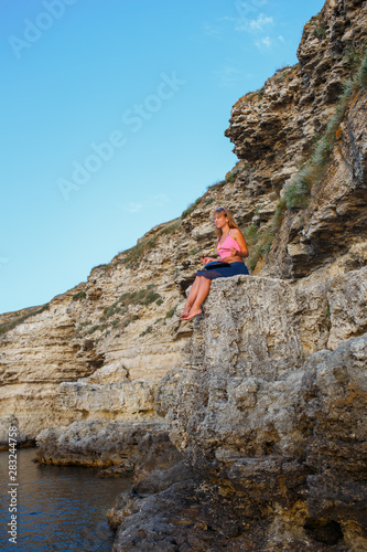 Girl playing a glucophone on a rocky seashore