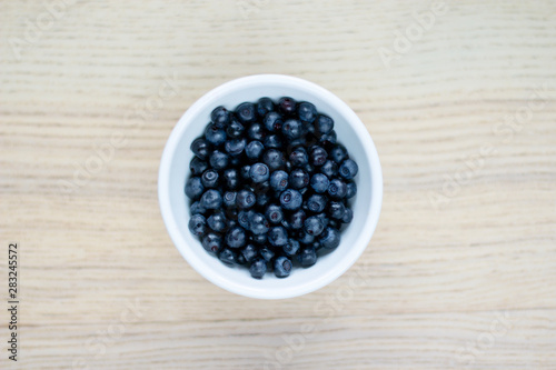 white bowl with blueberries on a light wooden table