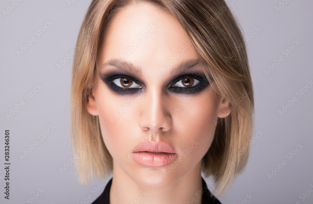Interesting fashion model and strong makeup on her face. Horizontal studio shot. Interesting fashion model and strong makeup on her face. Horizontal studio shot.