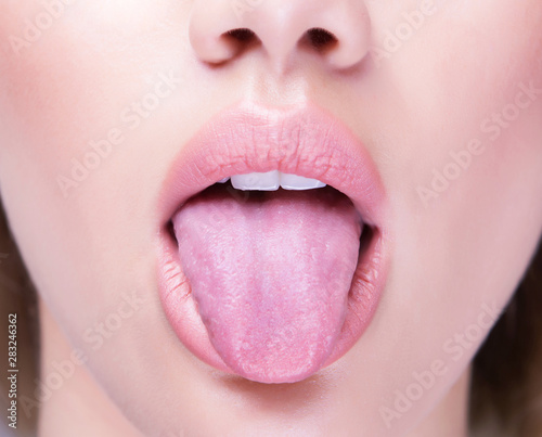 Close up shot of an open mouth and a healthy human tongue.