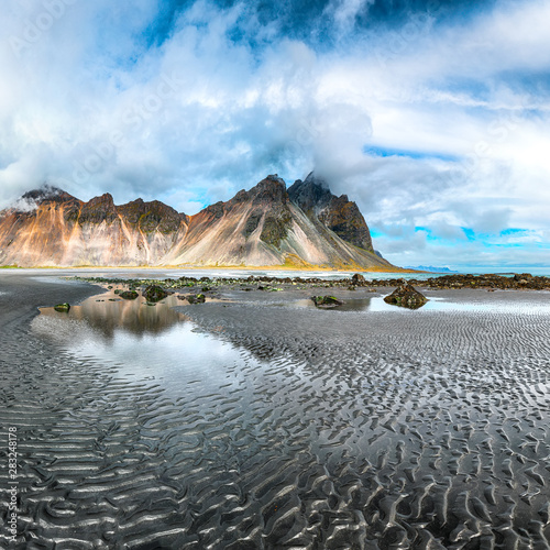 Dramatic sunny day and gorgeous rippled black sand beach on Stokksnes cape in Iceland.