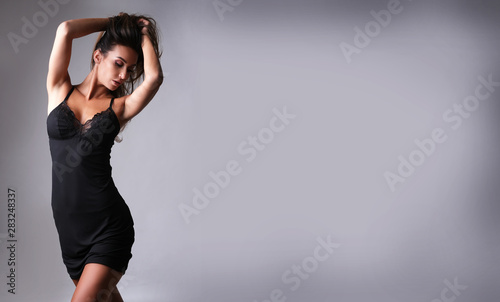 Beautiful woman looking hot in tight satin nightwear isolated on grey background  photo