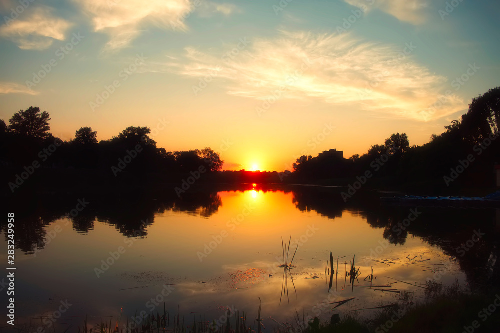 Natural summer river landscape. Sunset over the river. The sun is reflected in the water.