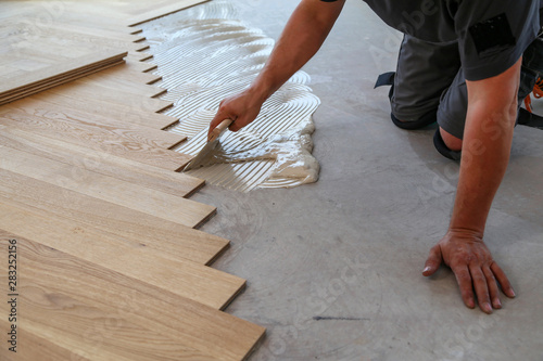 Worker laying parquet flooring. Worker installing wooden laminate flooring photo