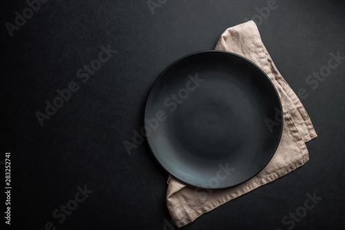 Elegant black table setting: plates, napkin and silverware over black background. Flat lay. copy space photo