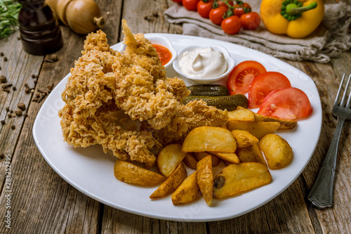 Chicken strips with ketchup and fried potatoes on wooden table. Turkish cuisine