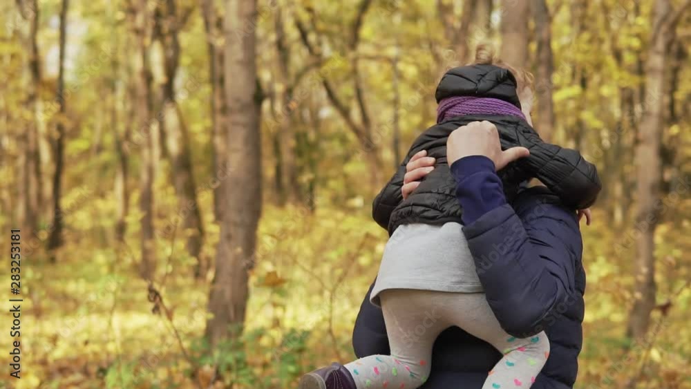 Little daugher in father's hands in autumn park. Daughter and young dad having fun together outdoors Little daugher in father's hands in autumn park. Daughter and young dad having fun together outdoors