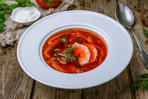 Borscht with sour cream on wooden table